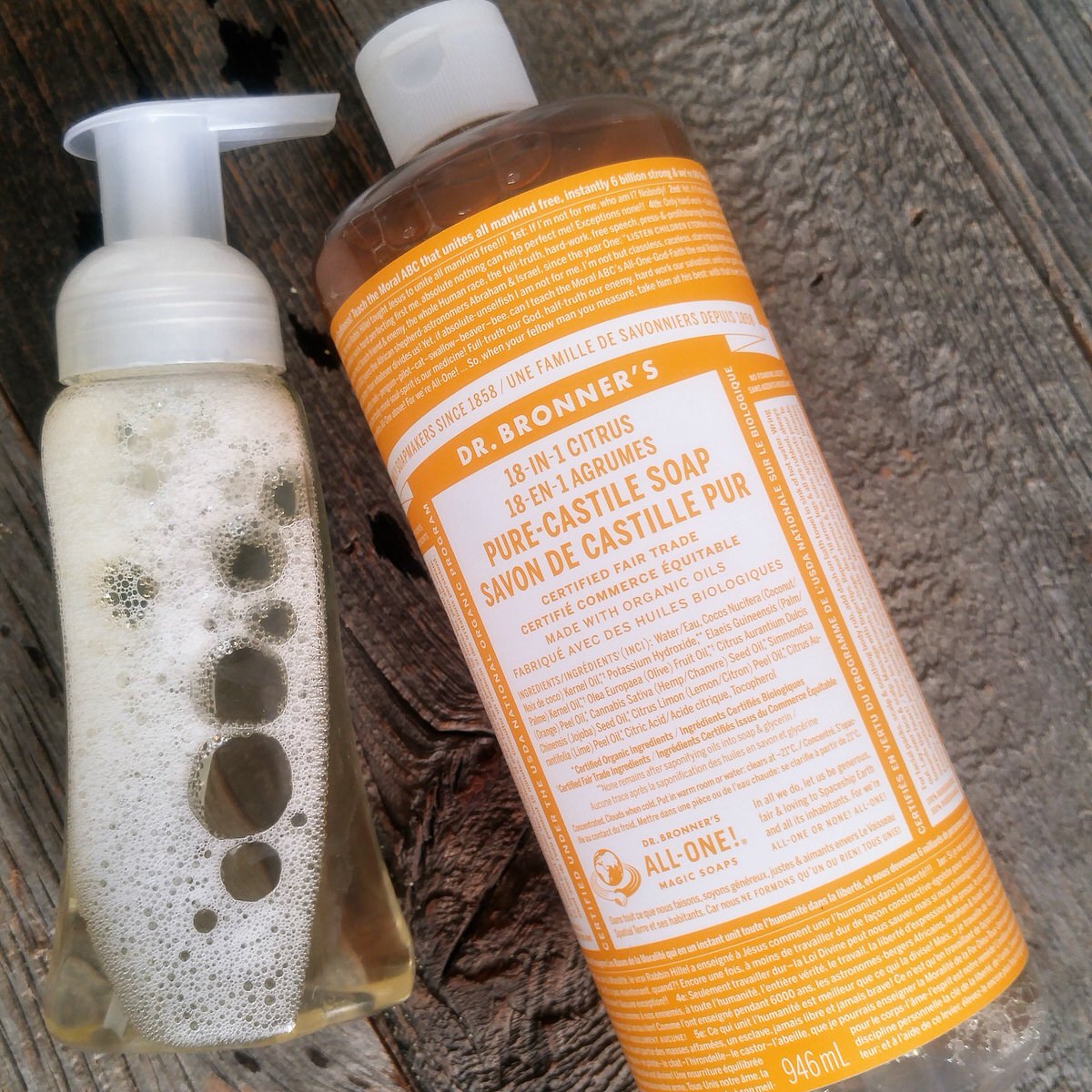 flat lay photo of a bottle of foaming hand soap and a bottle of orange castile soap on a rustic wood table
