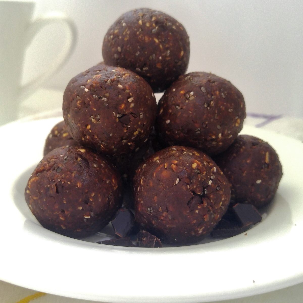 close up shot of a stack of chocolate peanut butter energy balls on a small white plate