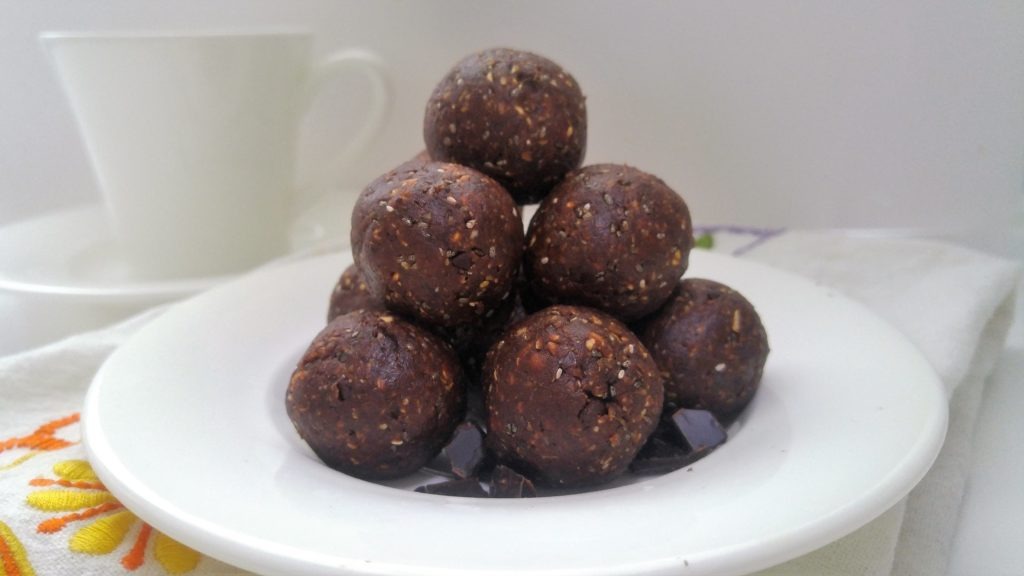 A small white desert plate is piled with energy balls