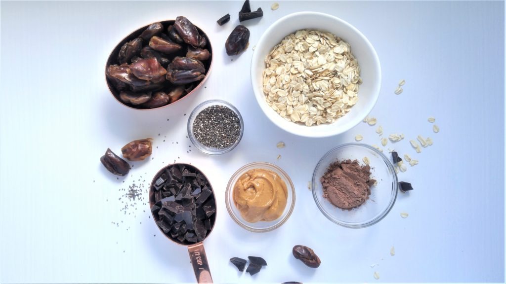 flat lay picture of bowls filled with dates, oats, chia seeds, cacao, and peanut butter