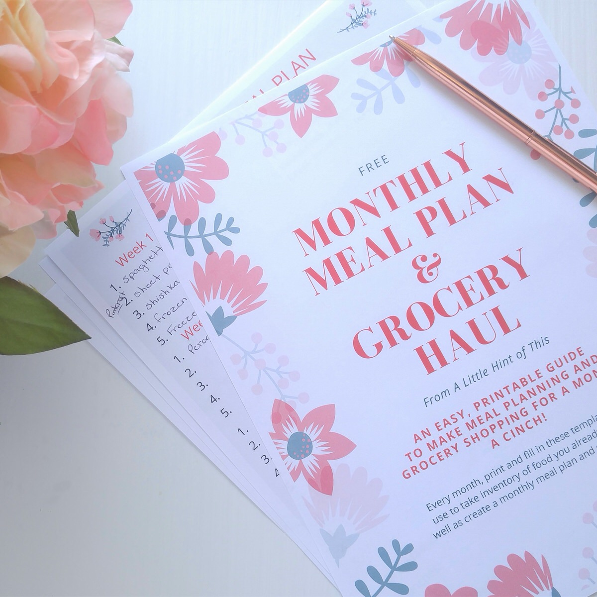 close up shot of meal planning printables on a white table beside a pink hydrangea