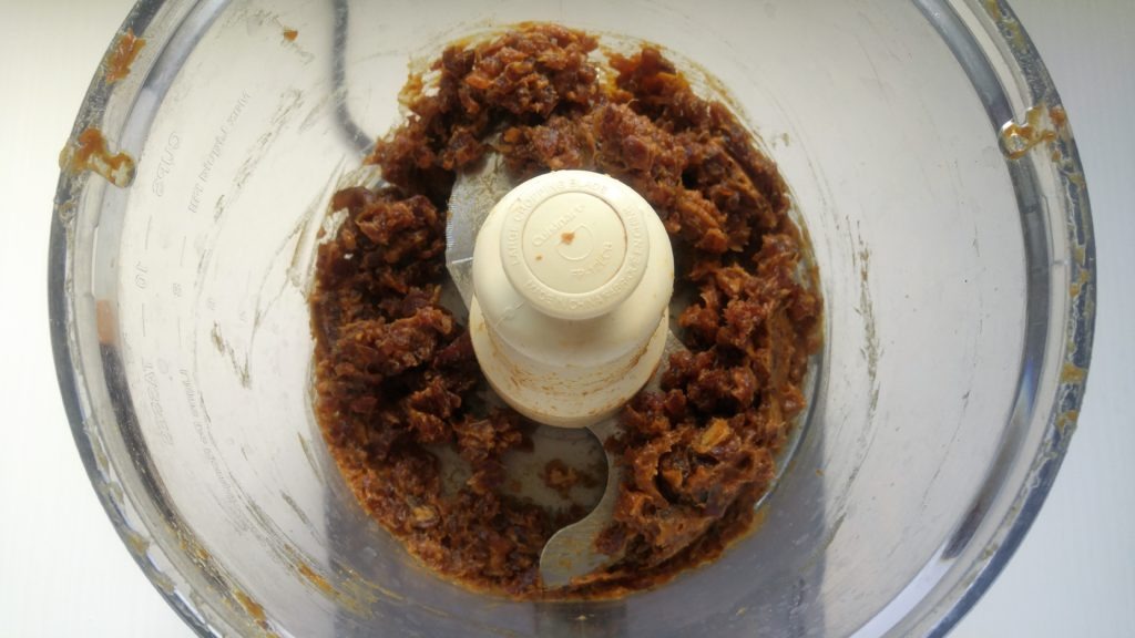 Looking inside a food processor at the pulsed dates.