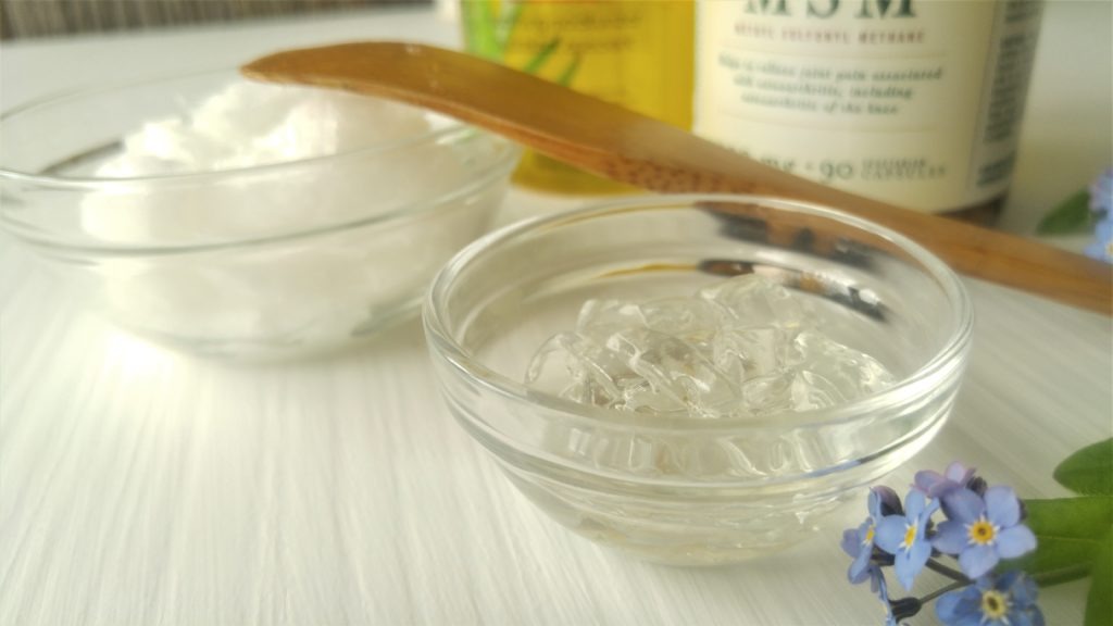 Close up of a small clear glass bowl of aloe vera gel and another bowl of white coconut oil.