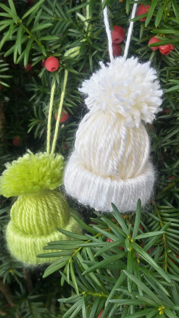 close up of a green and a white tiny winter toque made out of yarn.