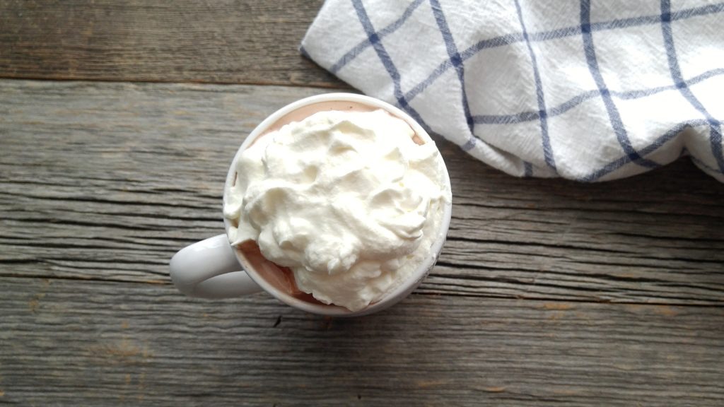 Top shot of a mug of hot chocolate full of whipped cream on top.