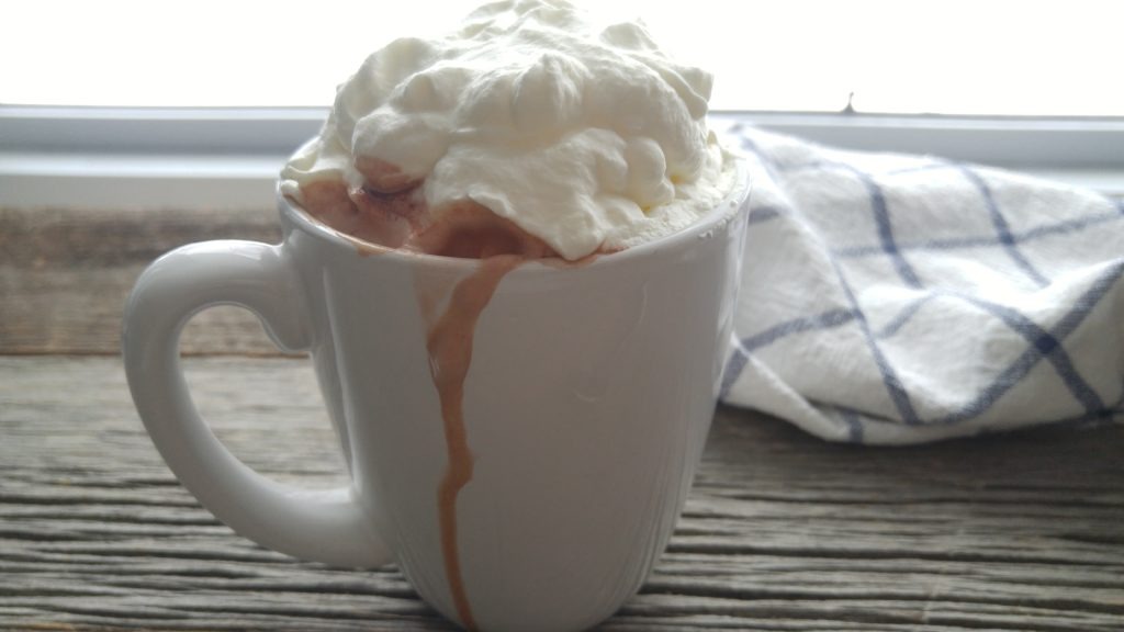 Close up of hot steamy mug hot chocolate topped with whipped cream