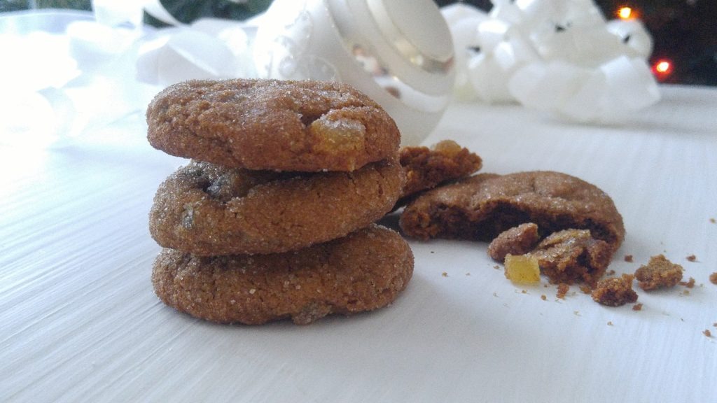 Close up shot of a stack of 3 gingersnap cookies on a table, with a broken cookie lying beside it.