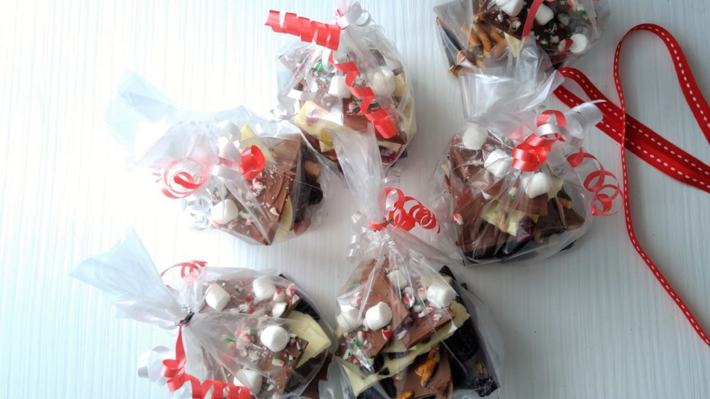 Packaged chocolate bark in clear bags with red and white curled ribbons.