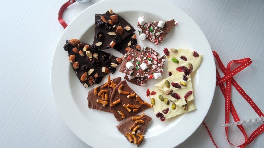A white plate holds multiple pieces of chocolate bark made with milk, white,and dark chocolate.