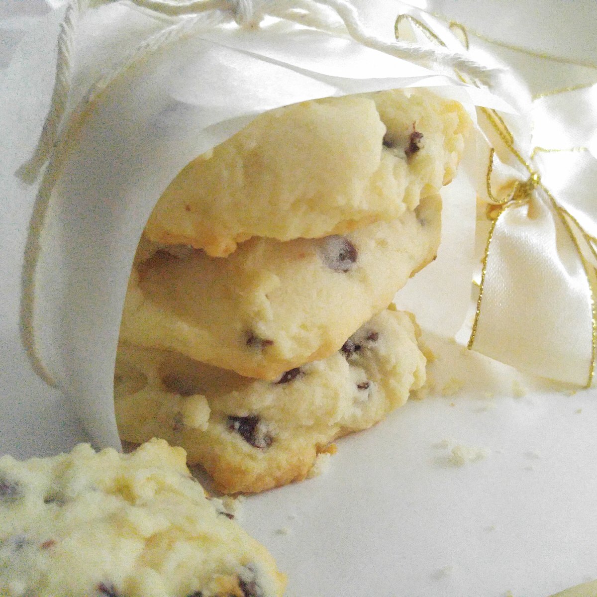 close up shot of three chocolate cherry shortbread cookies partially wrapped in parchment paper