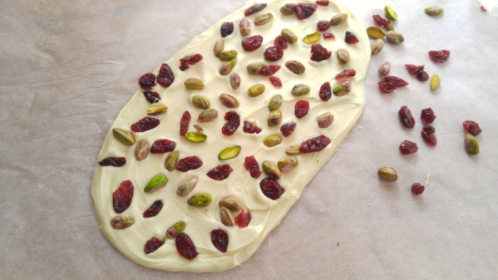 A close up picture of cranberry pistachio white chocolate bark. It has not yet been broken, so it is a large oval shape.