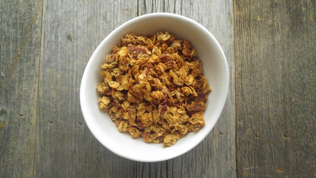 granola in a white bowl on a wooden table