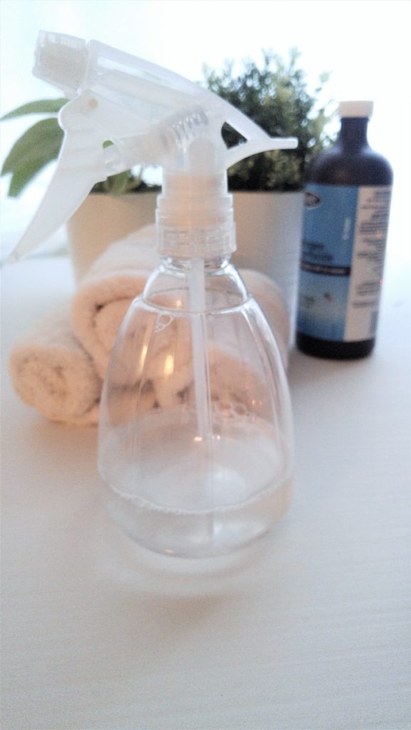 close up of a spray bottle containing stain remover, with hydrogen peroxide and white towels in the background