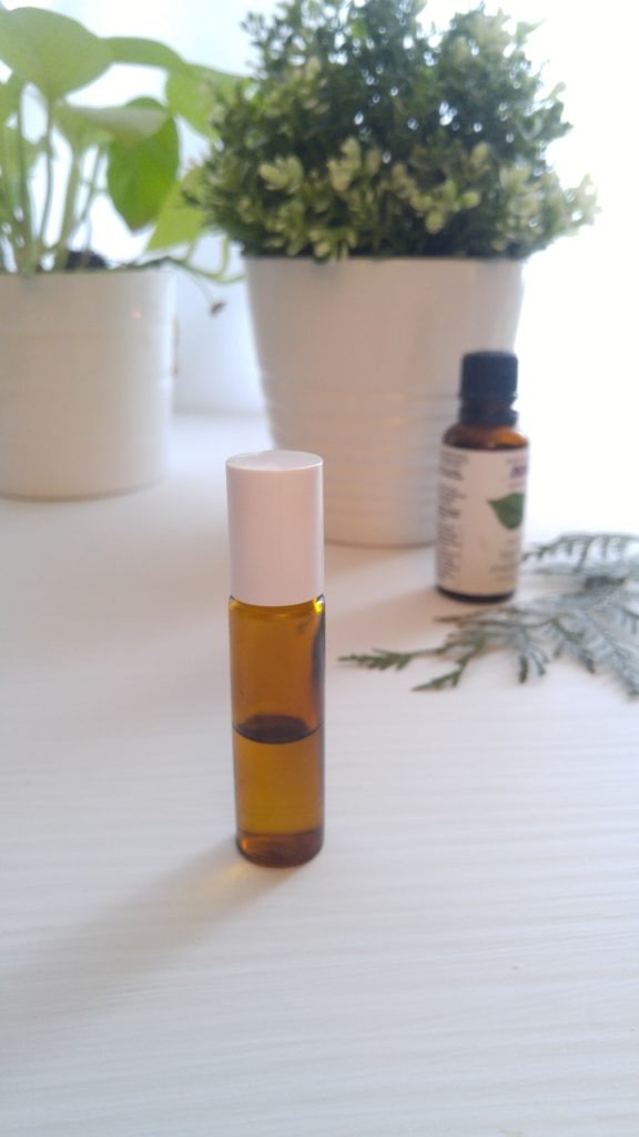 a roller bottle in the foreground, with a bottle of essential oils in the background.