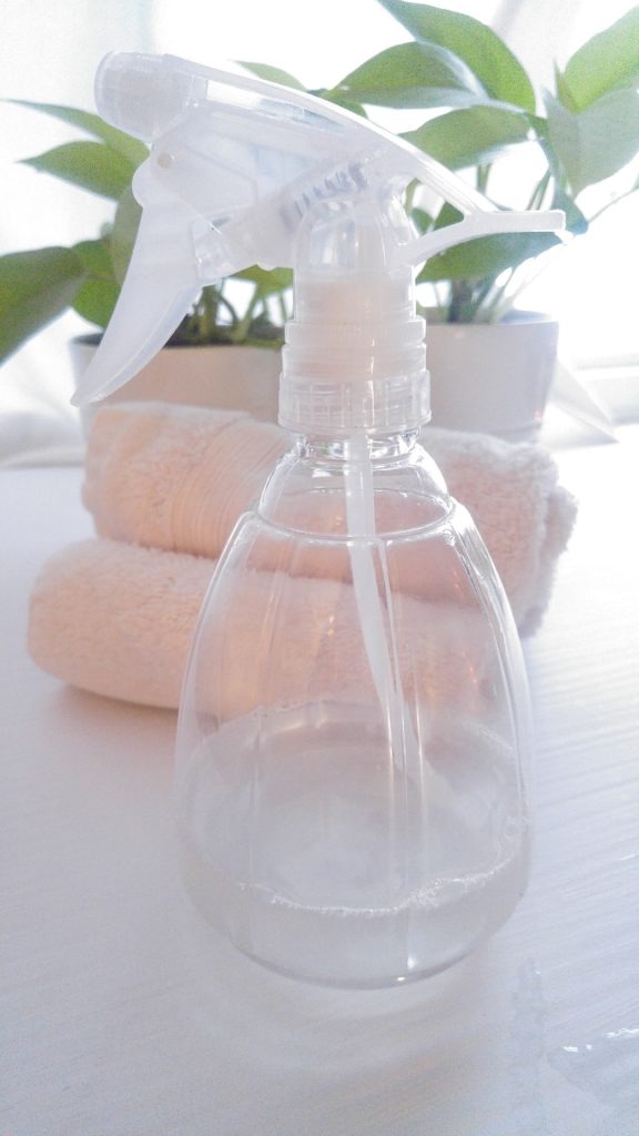 spray bottle with clear liquid inside it on a white table