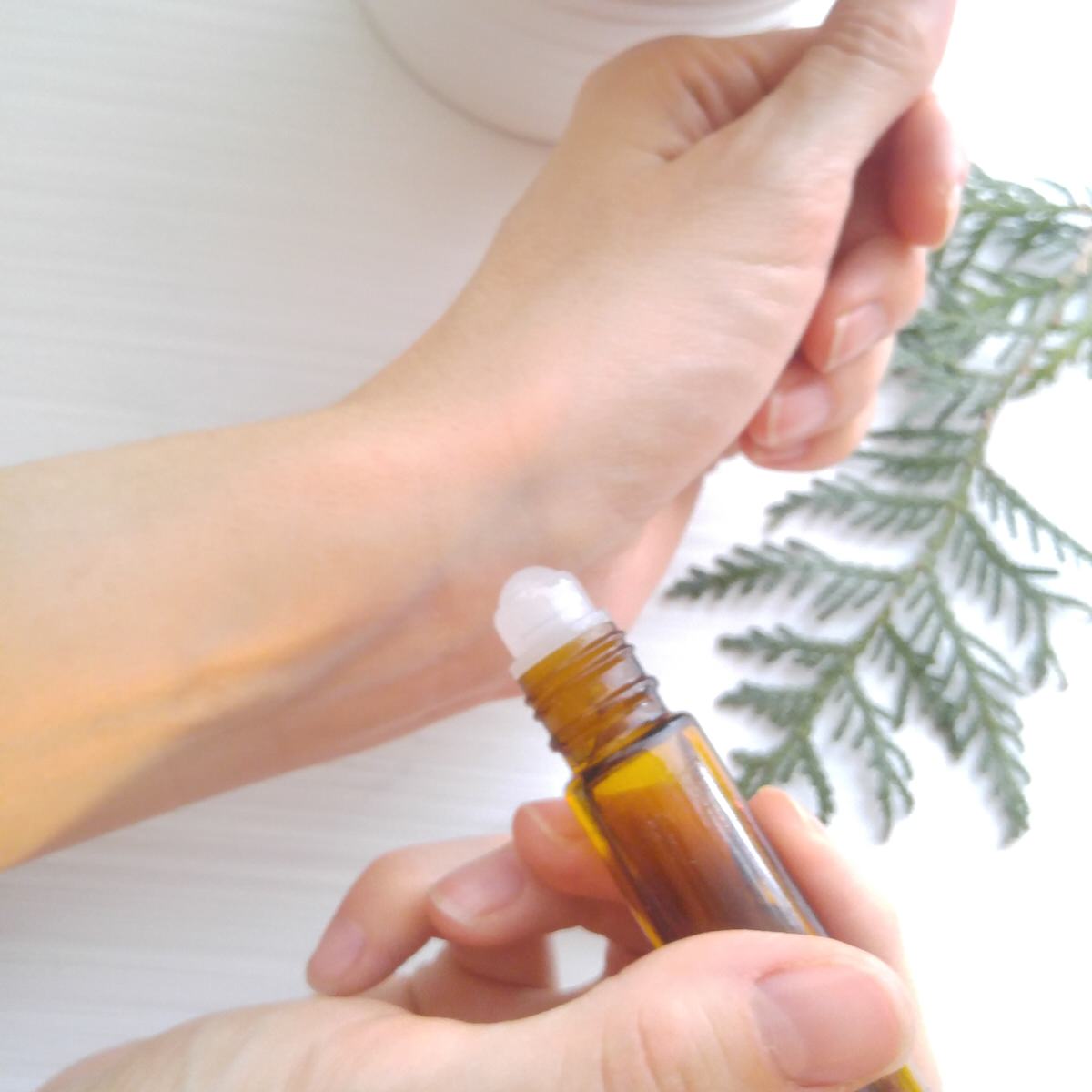 close up shot of a woman rolling an essential oil roller bottle onto her wrist
