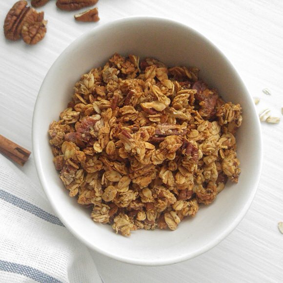 a white cereal bowl is filled with golden cinnamon granola
