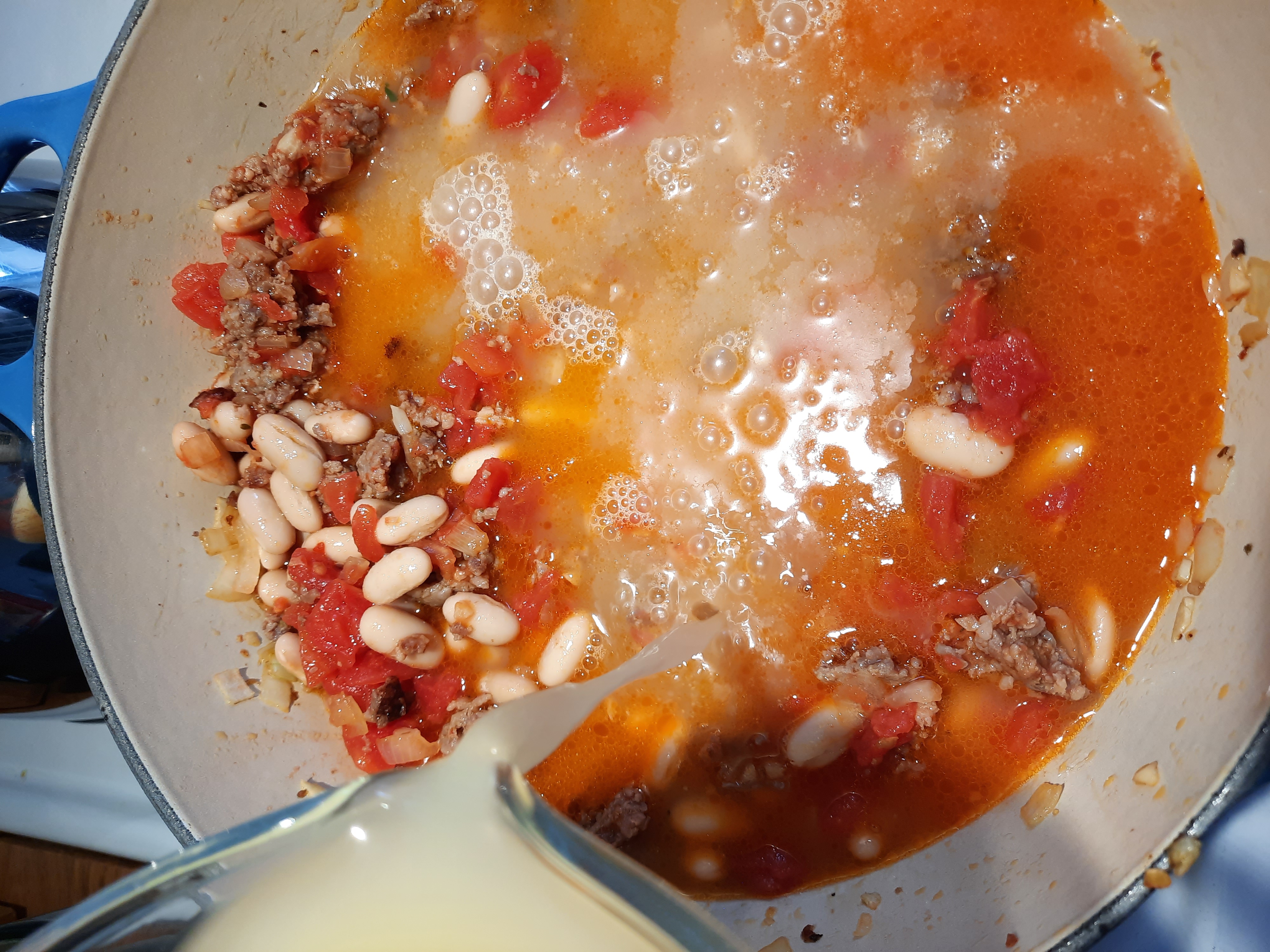 broth being poured into a pot of soup