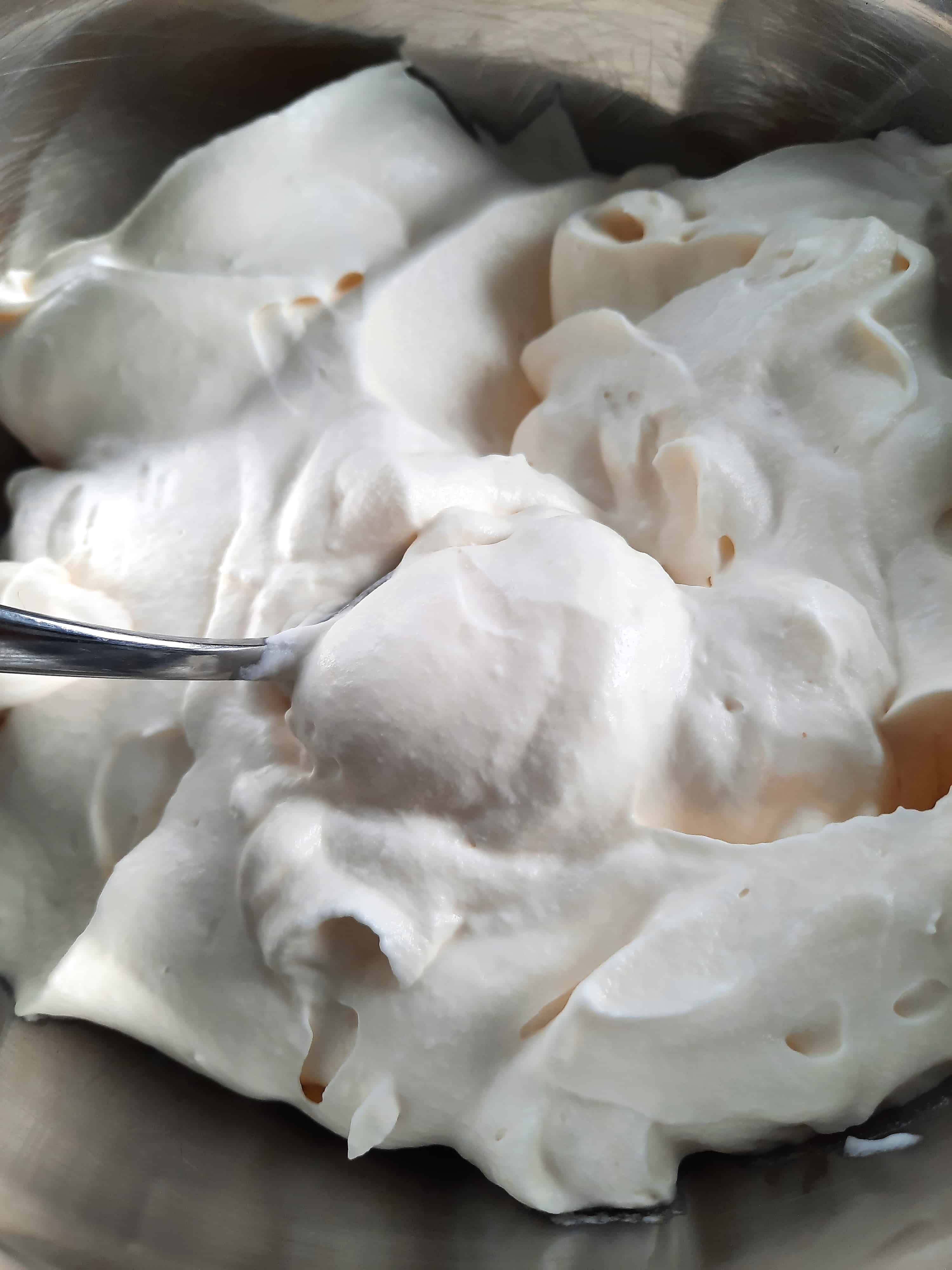 steel bowl full of fluffy stabilized whipped cream