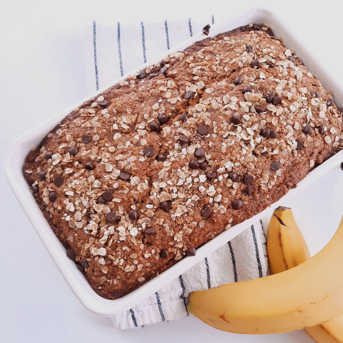fresh baked banana bread in a white pan sits on a white countertop
