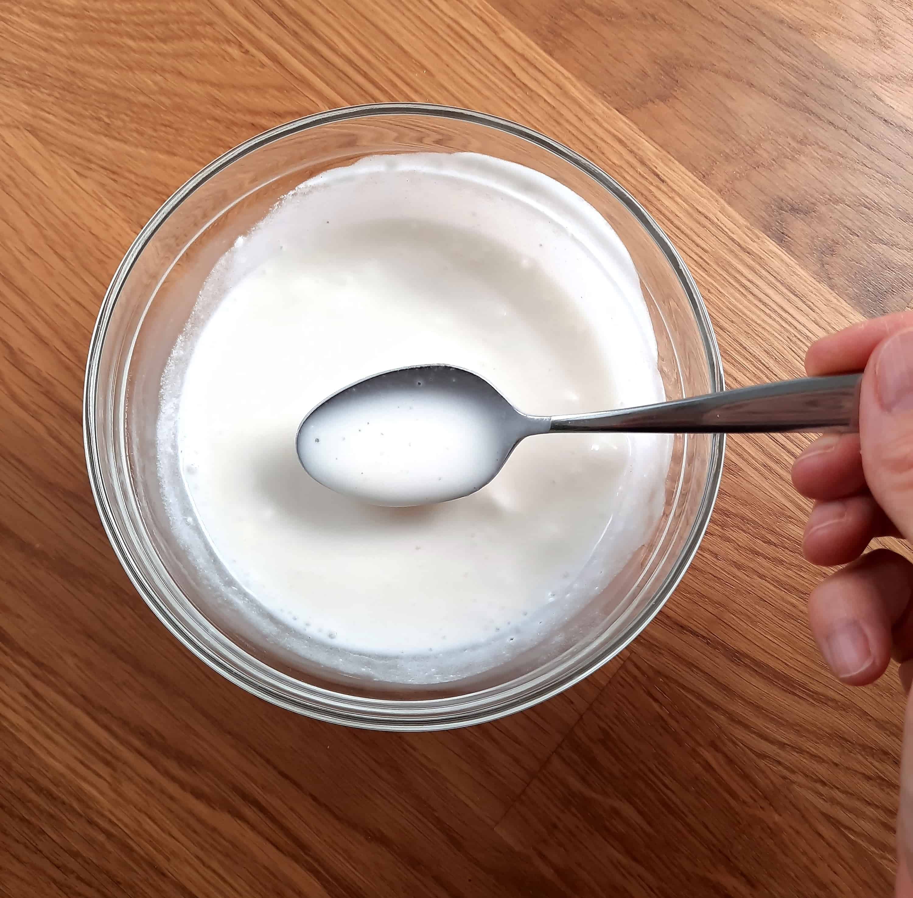 small spoon stirring white milky liquid