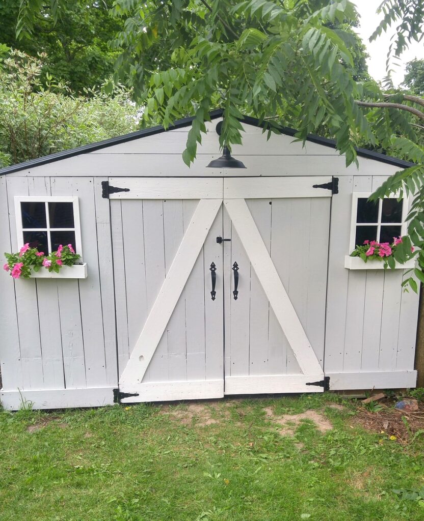 front view of a grey garden shed with white trim and flower boxes