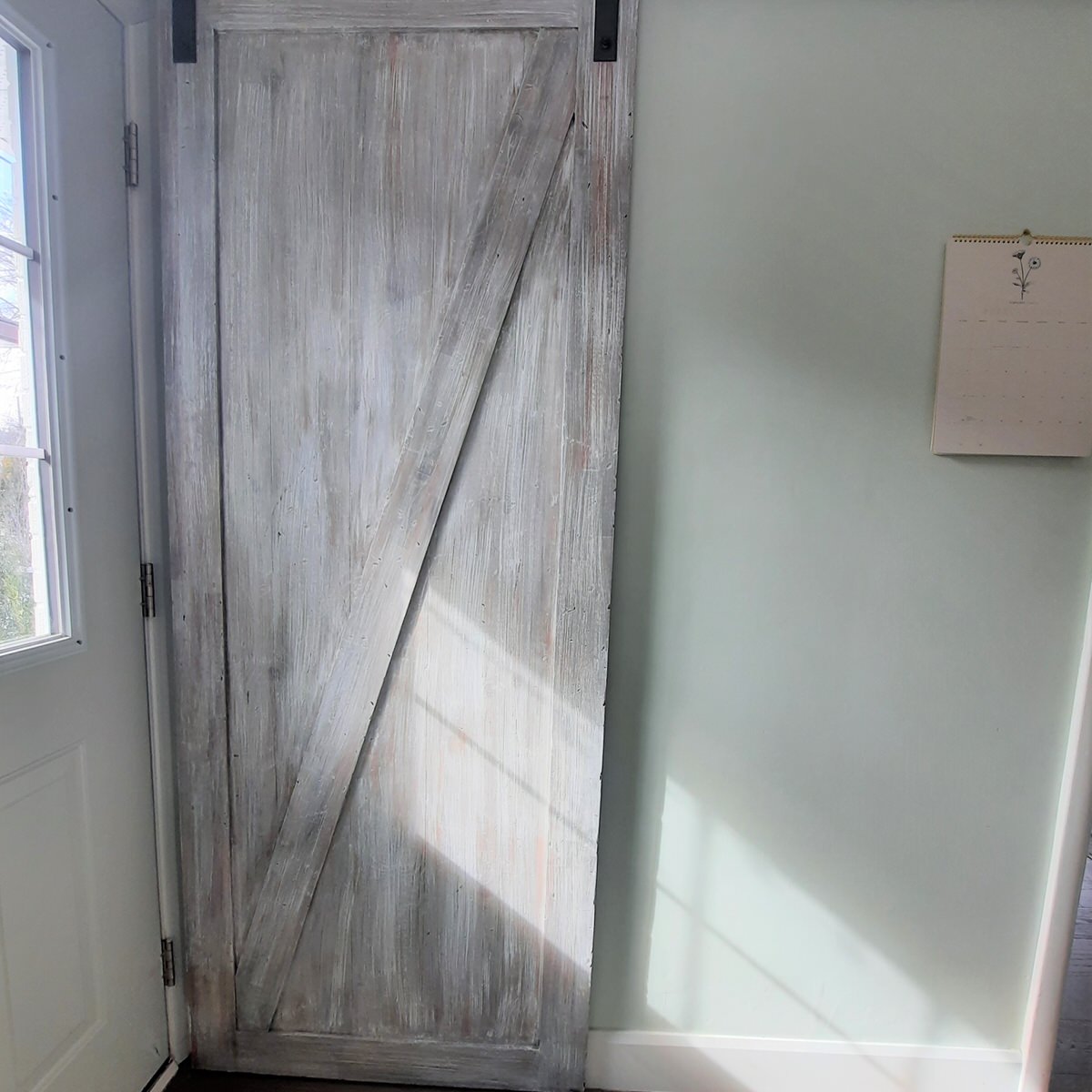 weathered grey barn door hanging on a soft green wall