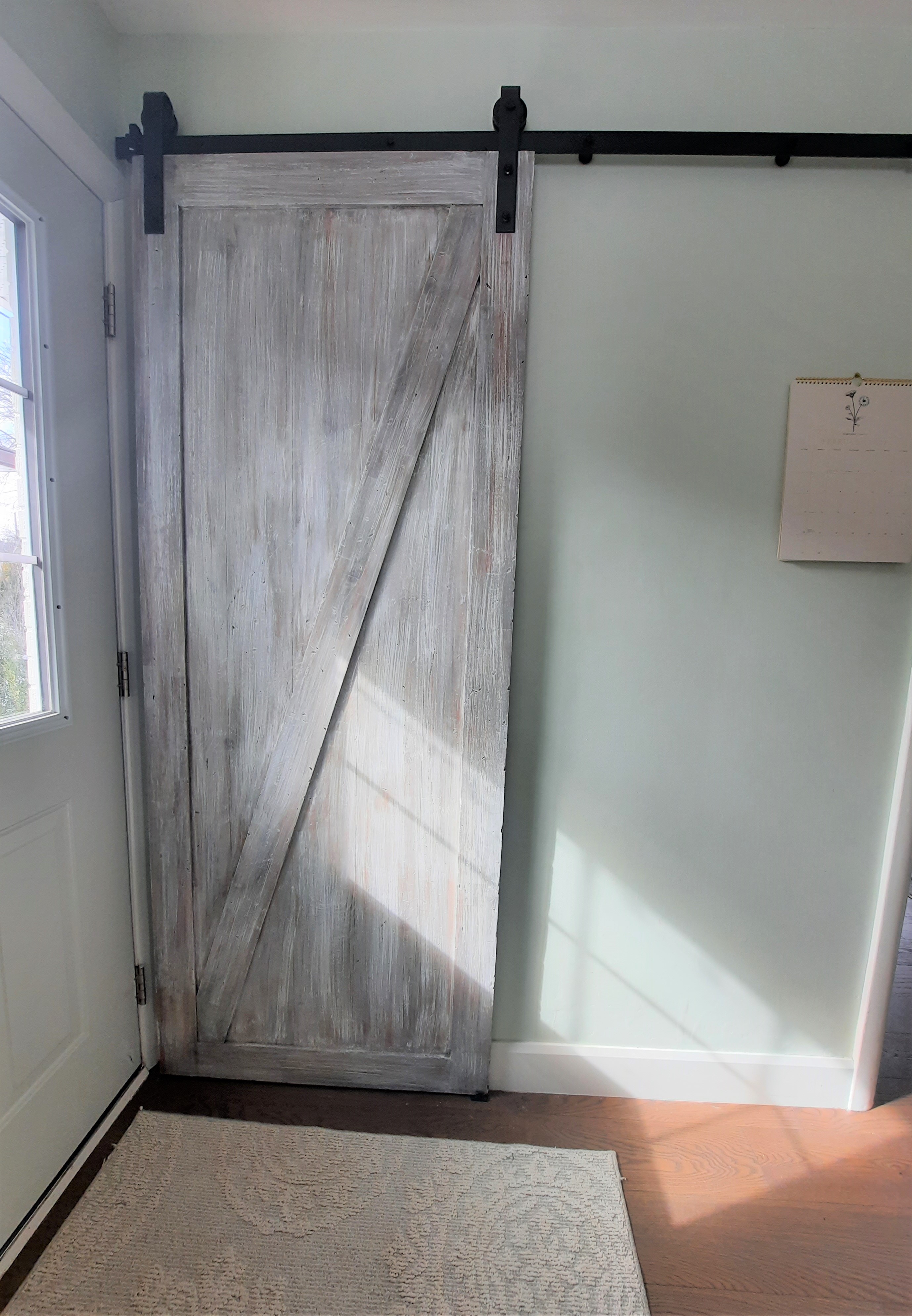 weathered wood barn door hanging on a soft green wall