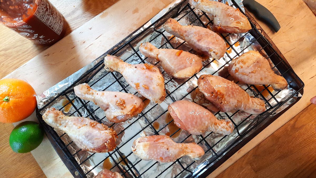 raw marinated drumsticks on a wire rack over a baking sheet