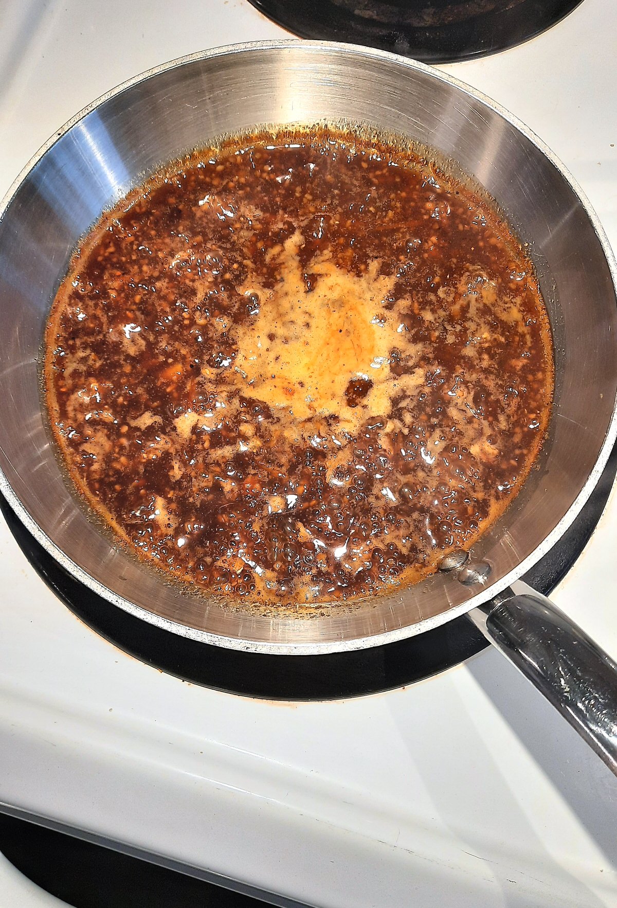 simmering pan of sticky and sweet chicken marinade on the stove top