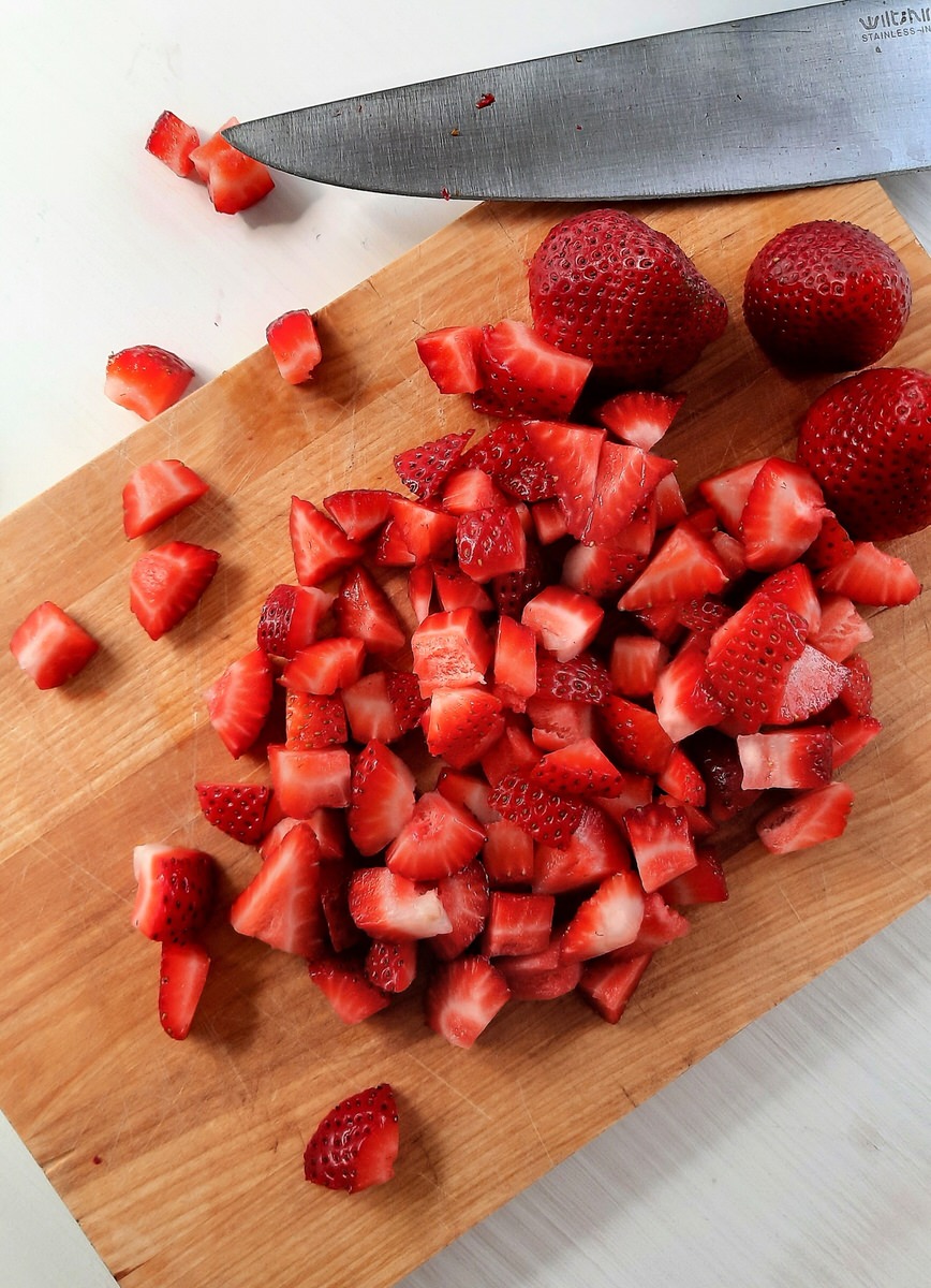 chopped strawberries on a wooden cutting board