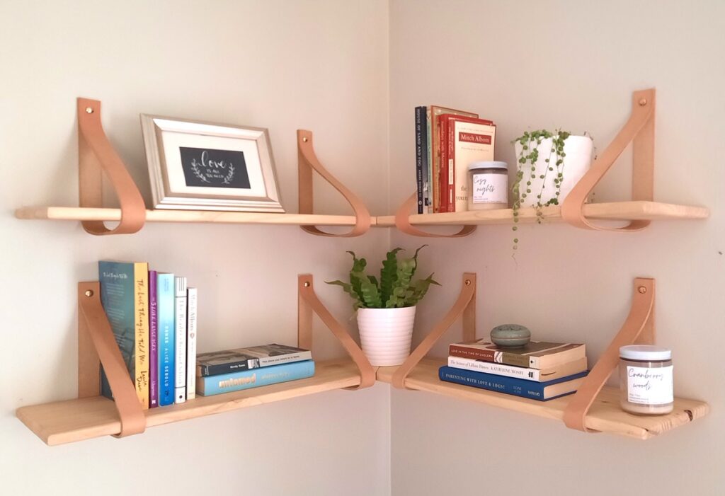 two pine corner shelves are held up by leather straps as brackes