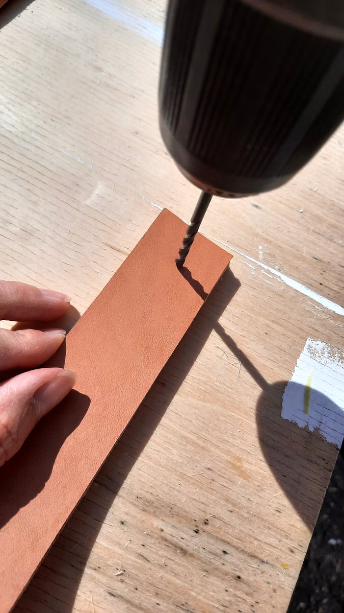 drilling a small hole into two layers of leather strap for corner shelf brackets