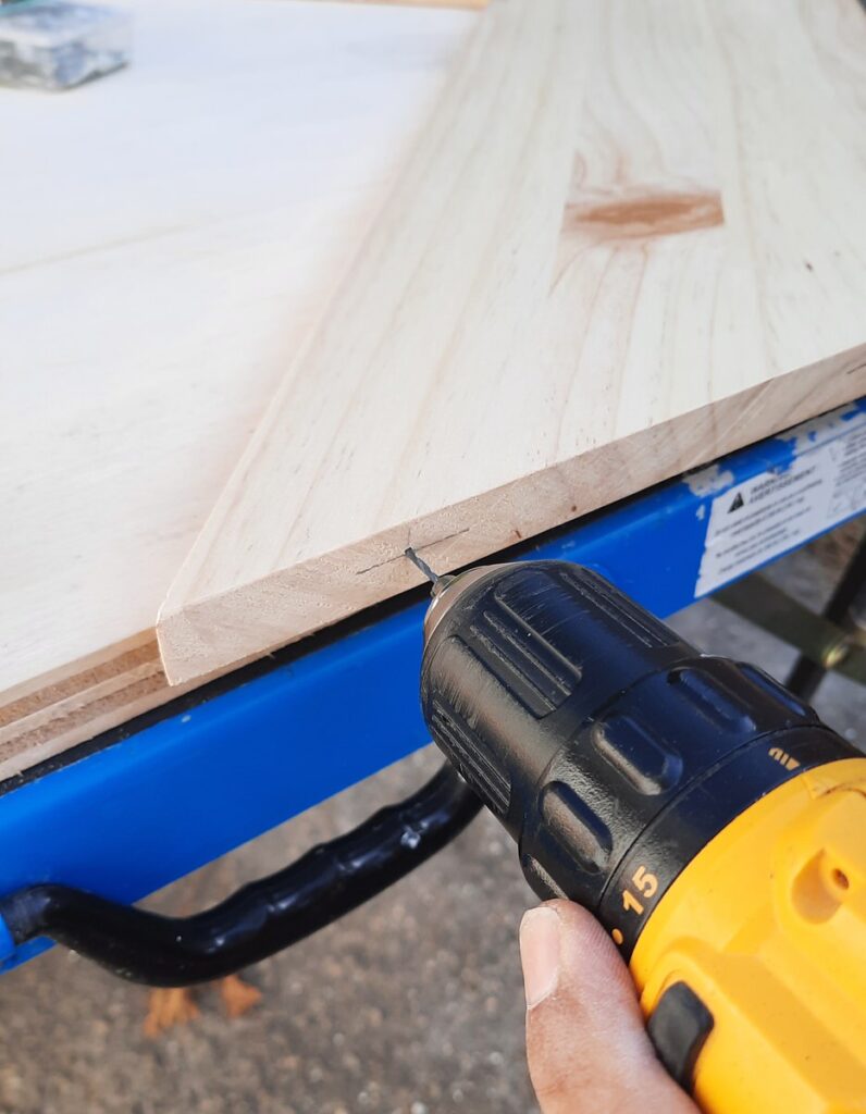 drilling small holes into the edge of a pine board