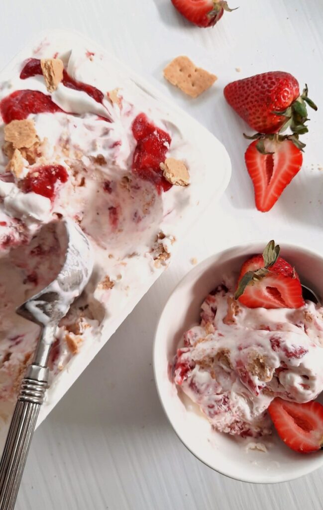 a white bowl and a white loaf pan both full of strawberry cheesecake ice cream