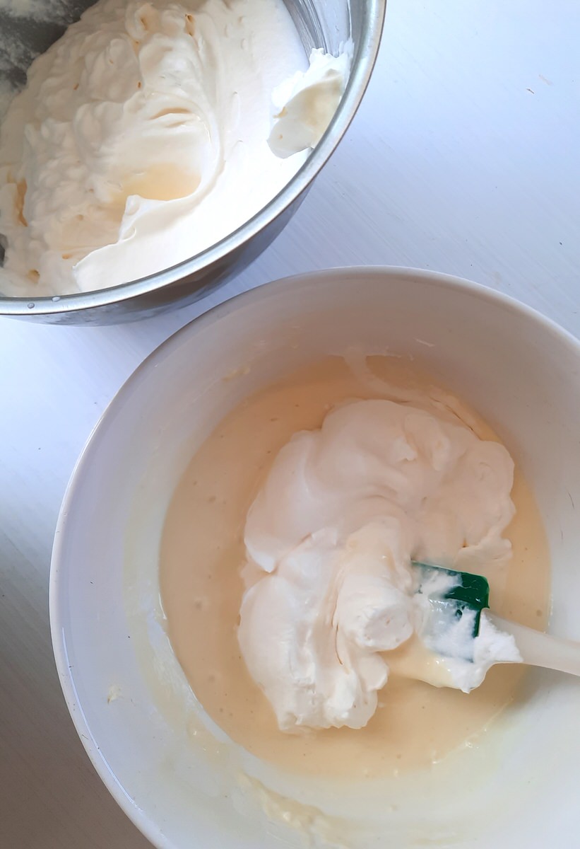 a spoonfull of whipped cream sits in a bowl with a mixture of condensed milk and cream cheese