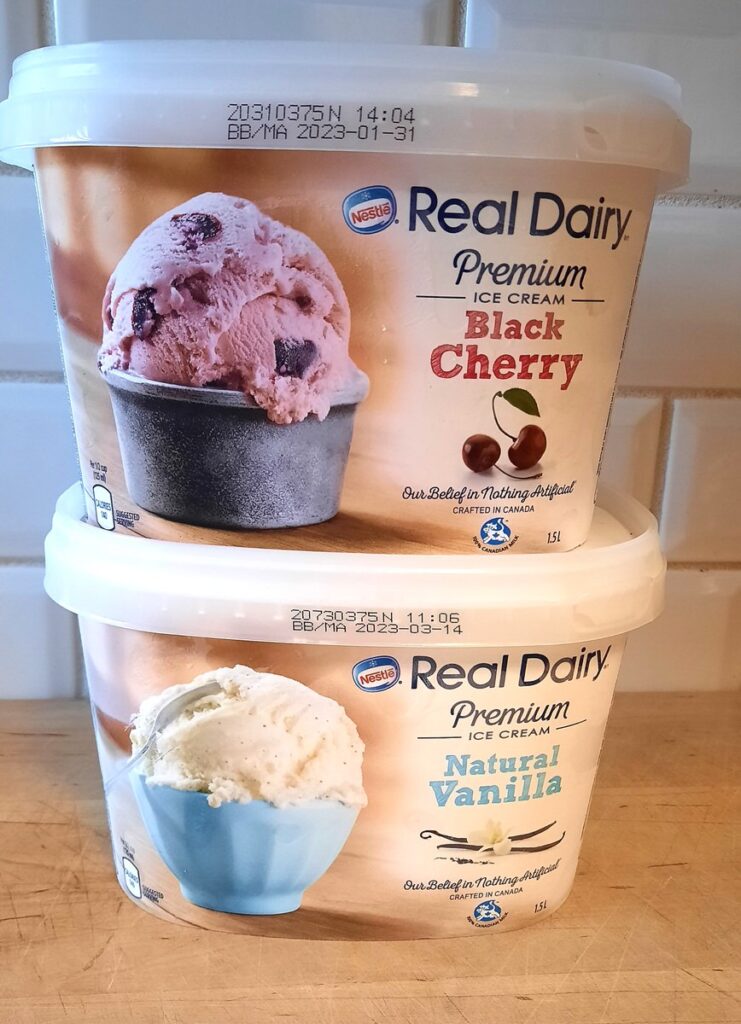 two tubs of ice cream sit on a counter. One is cherry flavour, the other is vanilla.