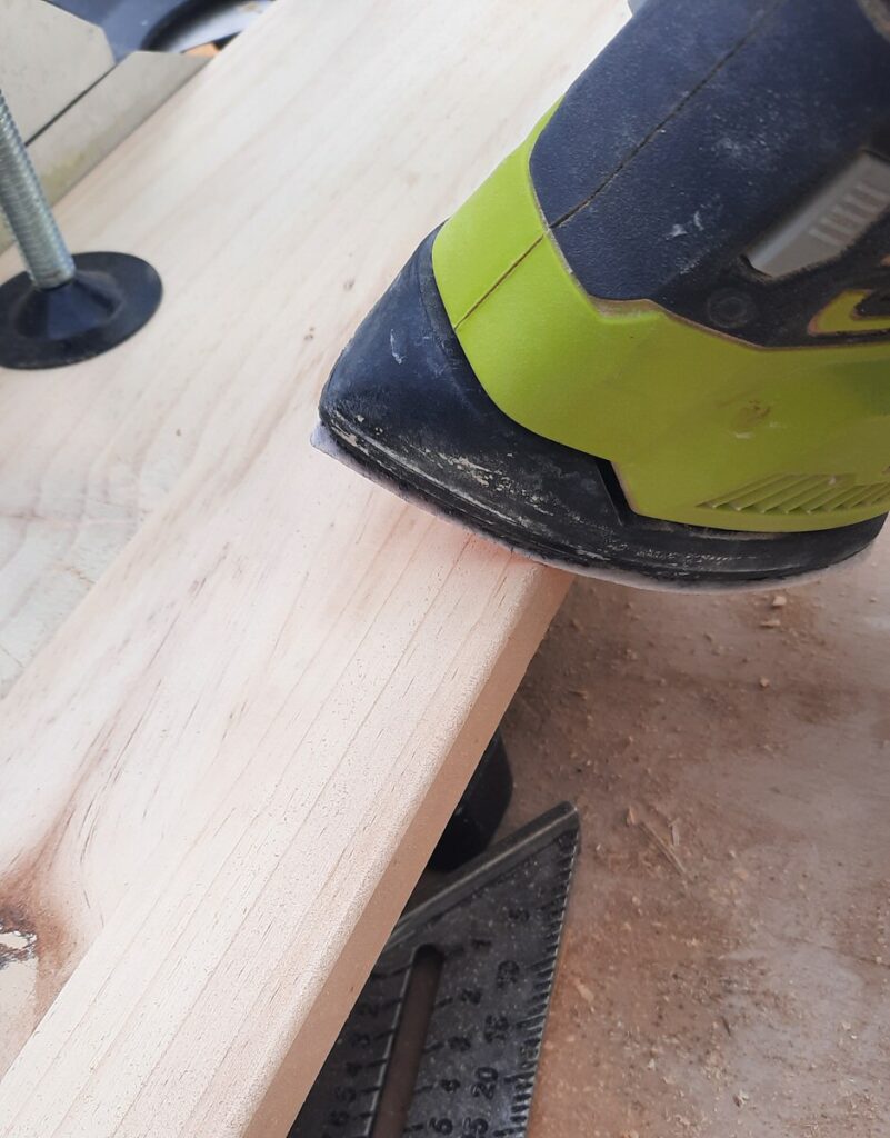 electric sander sands the edges of pine shelving board