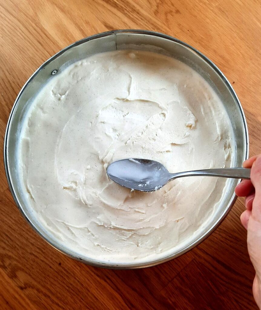a person spreads ice cream into a springform pan, smoothing the top