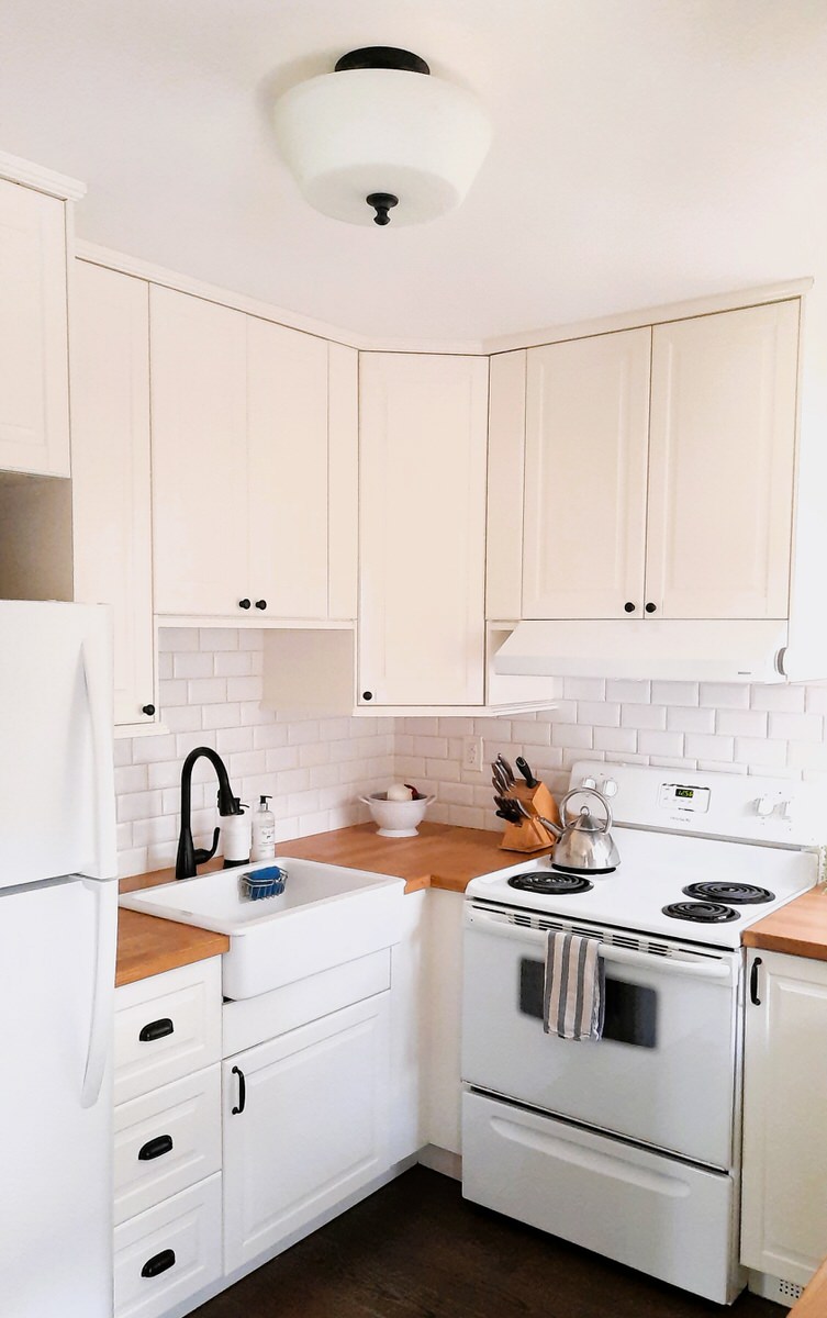 view of entire small kitchen with white cabinets and wooden counter