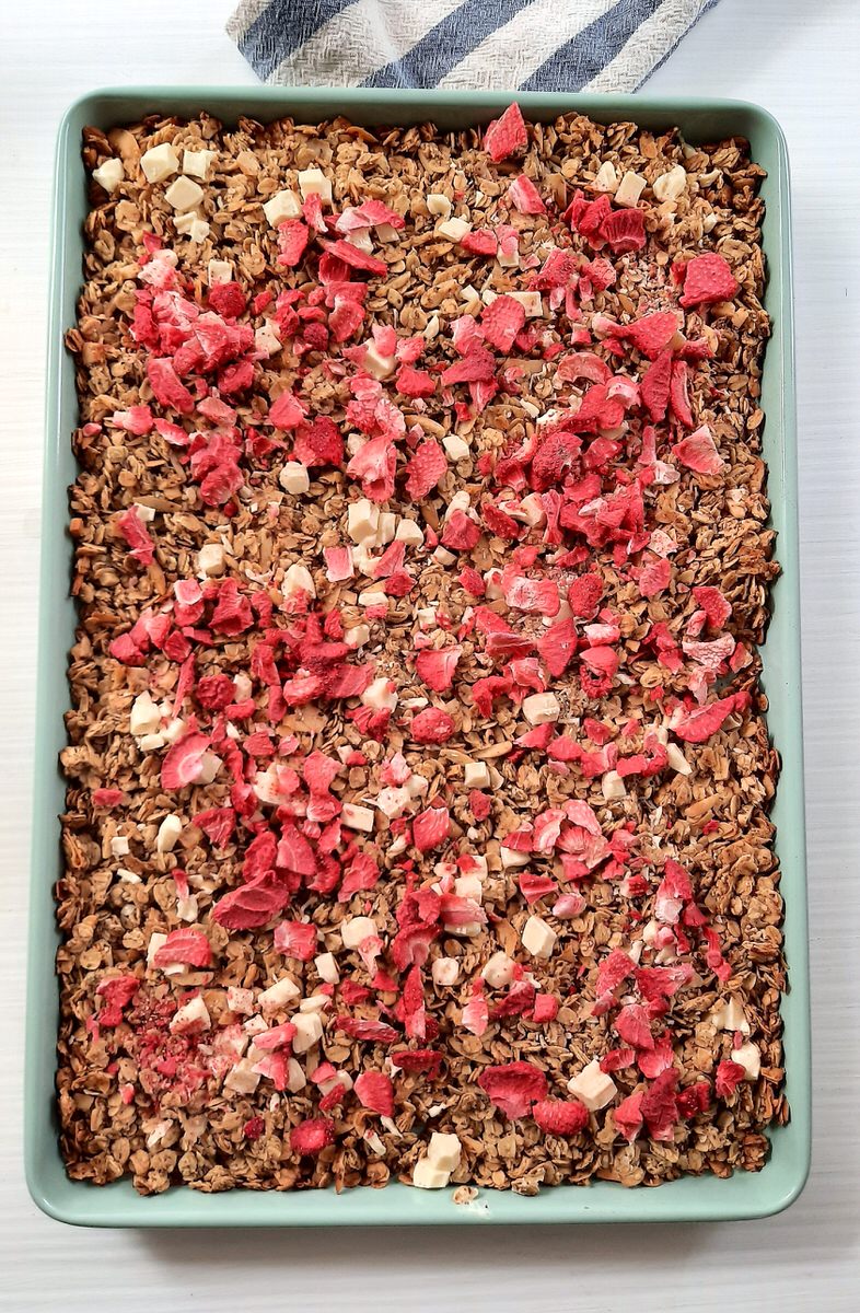 dried strawberries and white chocolate on baking sheet of granola
