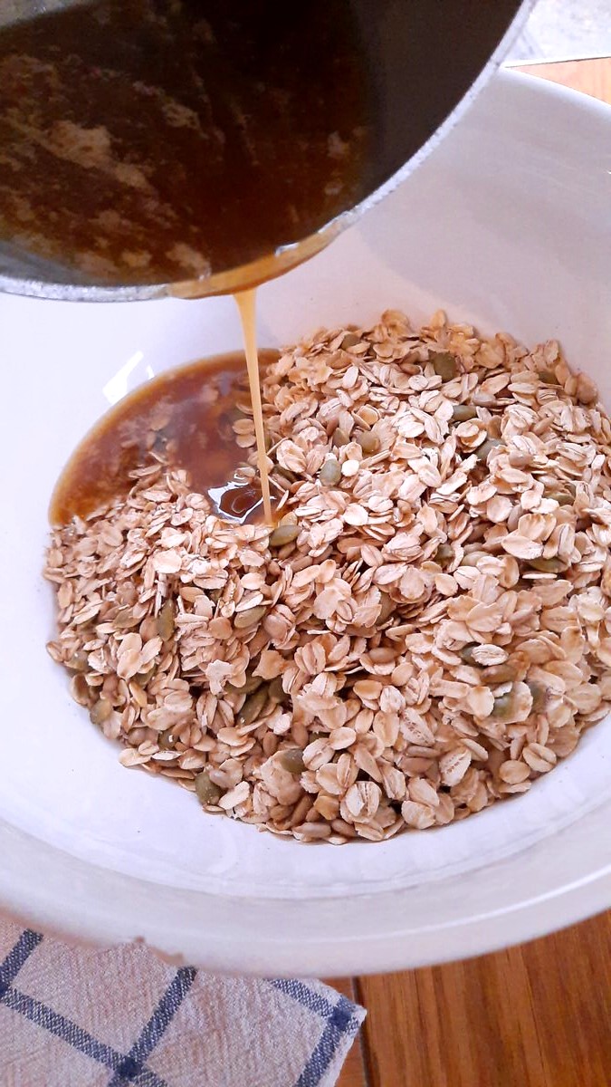 melted butter and sugar mixture being poured over dry oats mixture