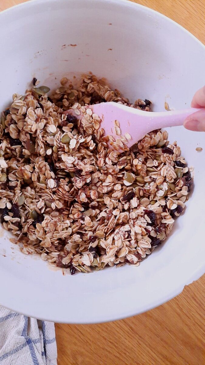 stirring granola bar mixture in a white bowl