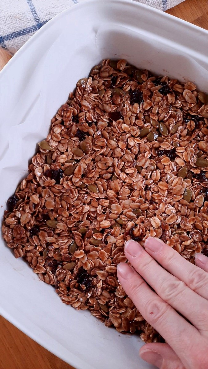 pressing granola bar mixture down with fingers
