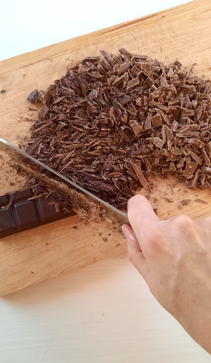 chocolate being finely chopped on a cutting board