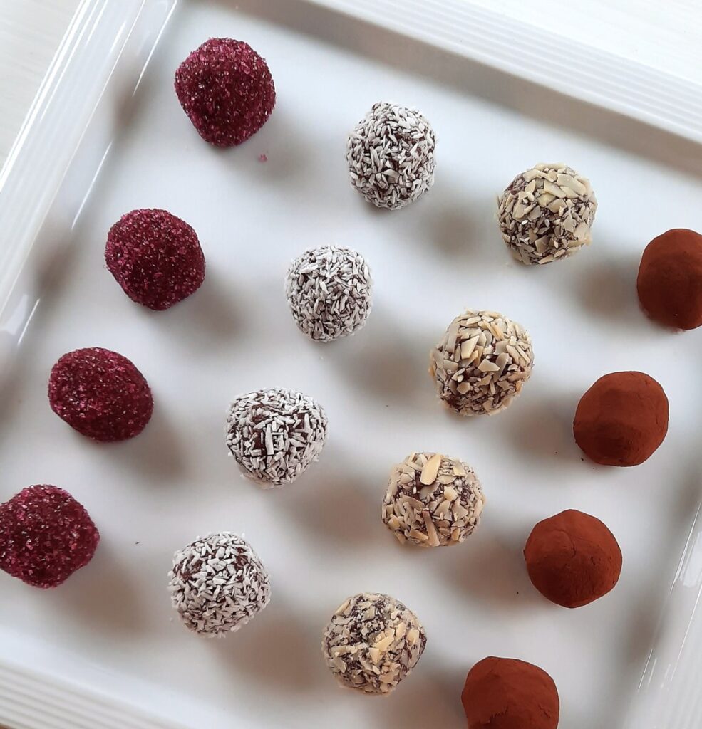 a platter with various types of chocolate truffles lined up on it