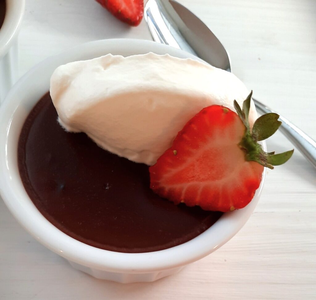 chocolate pudding topped with whipped cream and strawberries