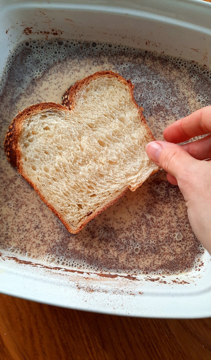hand dipping bread into custard mixture