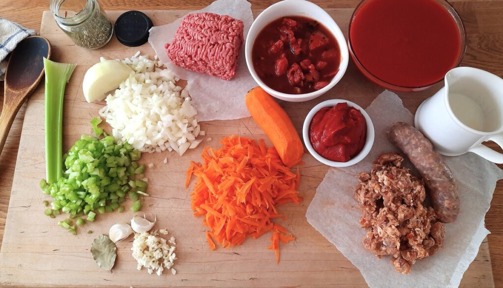 cutting board covered in raw pasta sauce ingredients