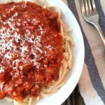 bowl of spaghetti and meat sauce on a rustic wooden counter